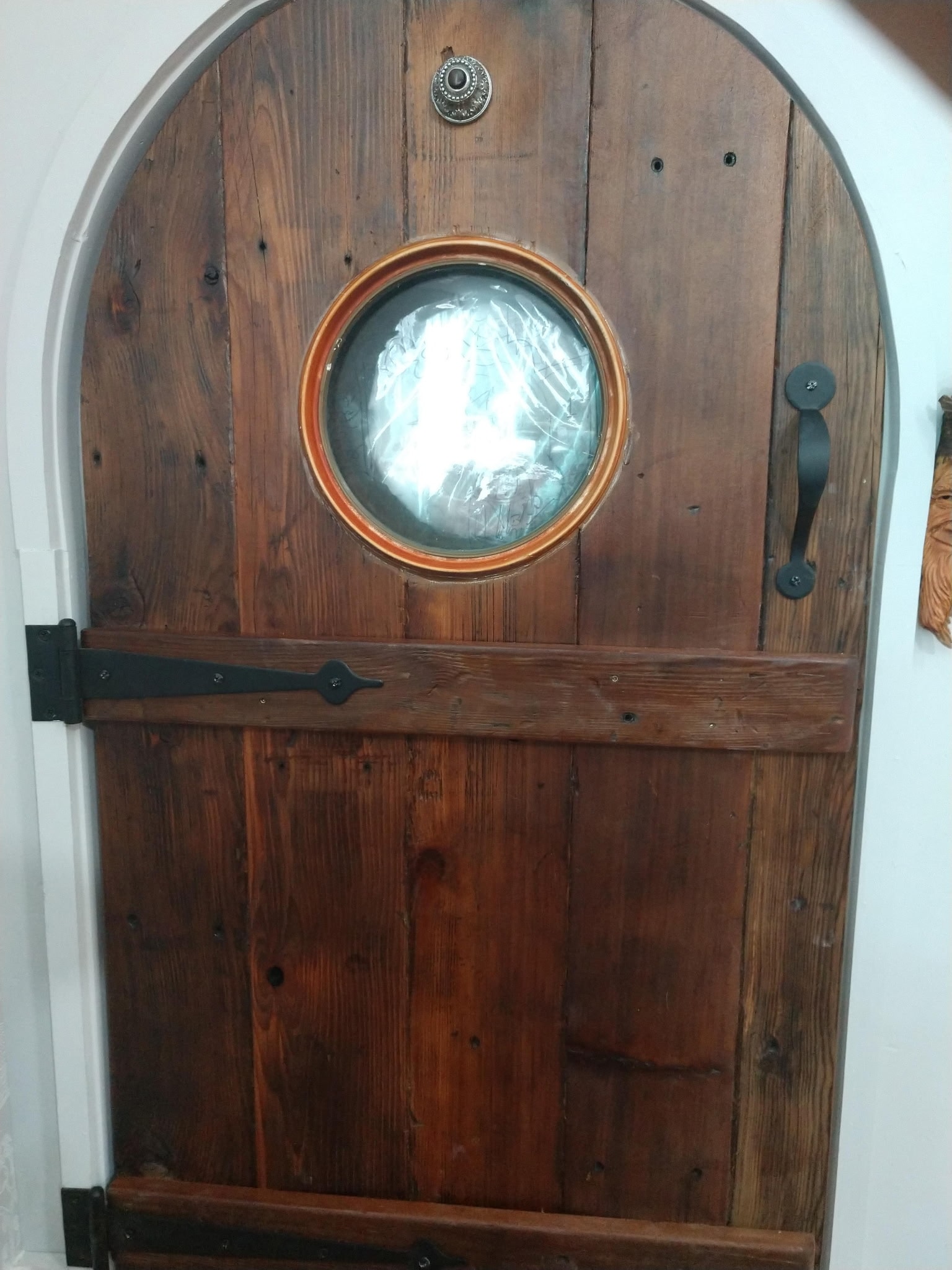 Custom wooden arched door with porthole window crafted by Outside the Box Construction