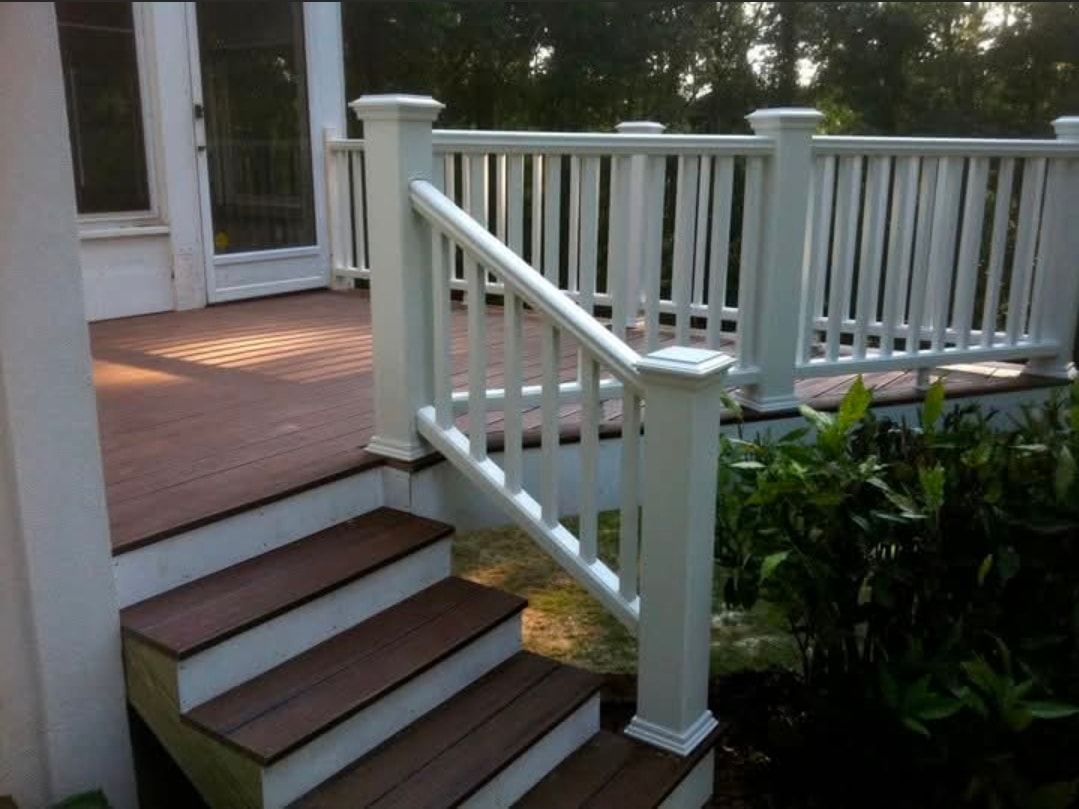 Custom wooden deck with white railing and stair entrance